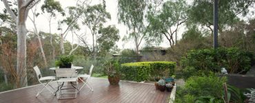 Un table et des chaises blanches sur une terrasse en bois dans le jardin