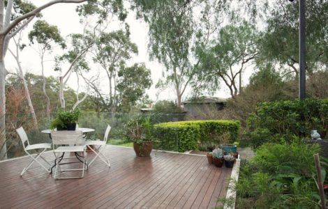 Un table et des chaises blanches sur une terrasse en bois dans le jardin
