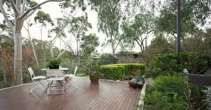 Un table et des chaises blanches sur une terrasse en bois dans le jardin