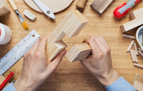 Un homme tient dans ses mains deux éléments en bois pour un assemblage en croix