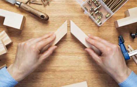 Zoom sur les mains d’un homme assemblant deux éléments en bois sur la table