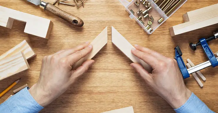 Zoom sur les mains d’un homme assemblant deux éléments en bois sur la table