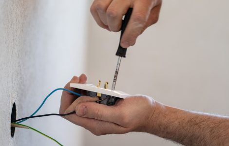 Un homme en train de réparer une prise électrique