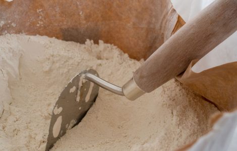 Gros plan sur une truelle et du plâtre placés dans un sac en papier ouvert