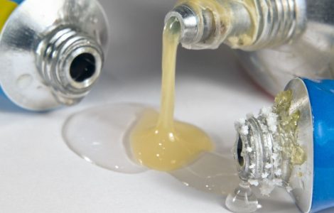 Trois tuyaux de colle déversés sur une surface plane