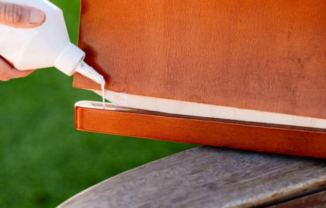 Une personne applique de la colle de bois sur deux éléments en bois