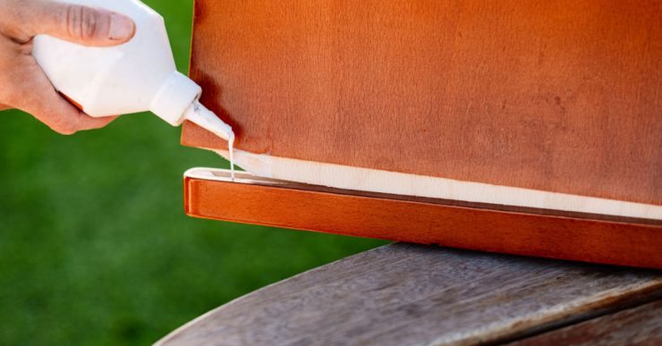 Une personne applique de la colle de bois sur deux éléments en bois