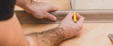 Un homme marque la plinthe au crayon avant la découpe et la pose