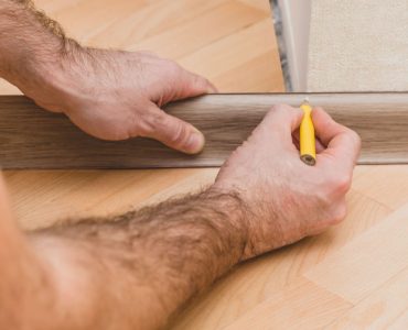 Un homme marque la plinthe au crayon avant la découpe et la pose