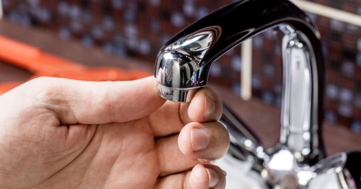 Zoom sur la main d'un homme retirant le mousseur d'un robinet