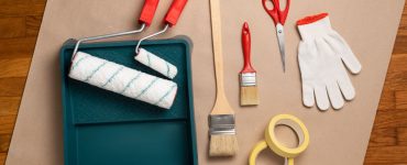 Différents outils pour la peinture posés sur la table : rouleau, pinceau, gant…