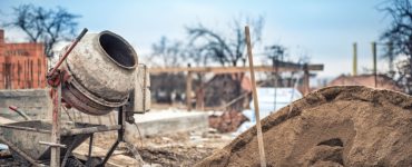 Une petite bétonnière, une brouette, une pelle et du sable dans un chantier