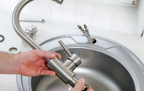 Gros plan sur les mains d'un homme tenant un nouveau robinet à installer sur l'évier