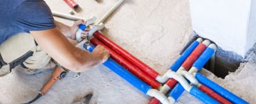 Un homme effectuant le raccord des tuyaux en PVC de différentes couleurs