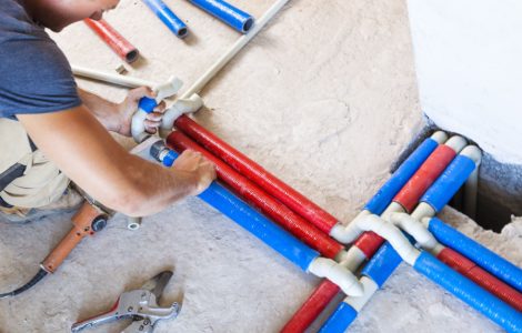 Un homme effectuant le raccord des tuyaux en PVC de différentes couleurs