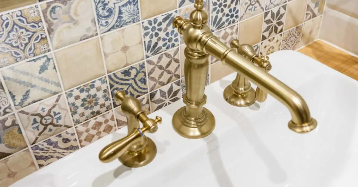 Vue sur les robinets en laiton et le carrelage mural multicolore d'une salle de bain
