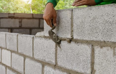 Un homme contruit un mur en parpaings avec sa truelle