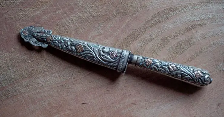 Un couteau de nickel argenté avec des motifs posé sur une surface en bois