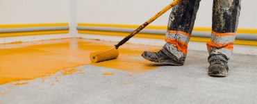 Un homme en train de peindre le sol en jaune grâce à son rouleau