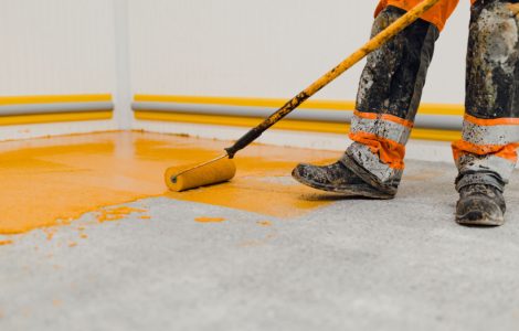 Un homme en train de peindre le sol en jaune grâce à son rouleau