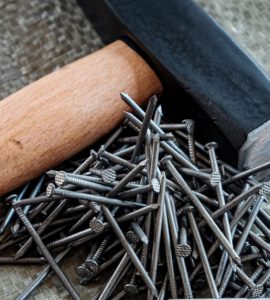 Un marteau avec manche en bois posé à côté de plusieurs clous