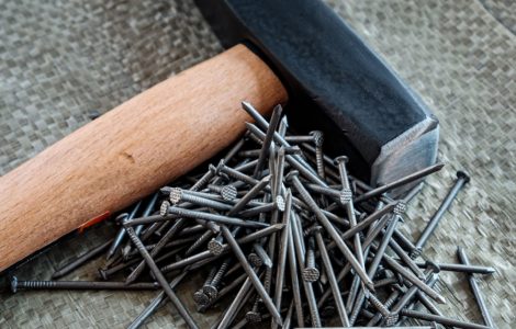 Un marteau avec manche en bois posé à côté de plusieurs clous