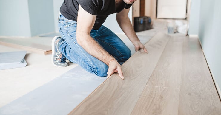 Un homme en casquette en train d’installer du parquet flottant