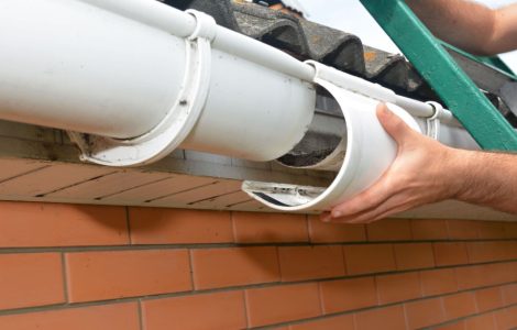 Zoom sur les mains d’un homme réparant la gouttière du toit