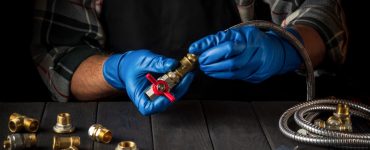 Un homme en gants bleus connecte les raccords en laiton d’un équipement de gaz