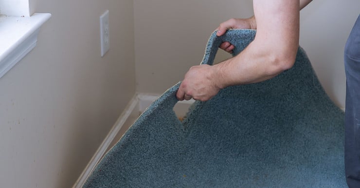 Un homme installant une nouvelle moquette de sol bleue