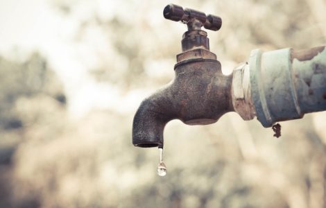 Zoom sur un vieux robinet extérieur qui goutte