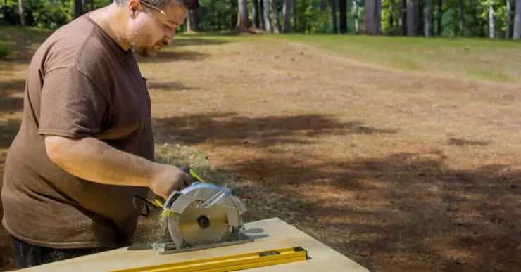 Un homme sciant une plaque de bois avec une scie circulaire