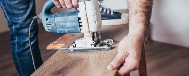 Un homme sciant un plancher avec une scie sauteuse