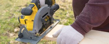 Un homme coupe une planche avec une scie circulaire