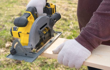 Un homme coupe une planche avec une scie circulaire