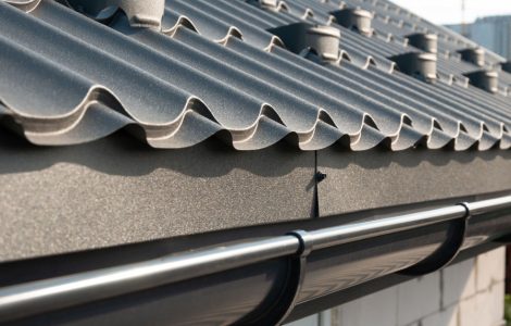 Zoom sur les tuiles de toiture en métal gris et la gouttière en zinc