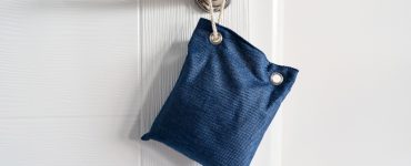 Petit sac bleu accroché à une poignée de porte par une corde