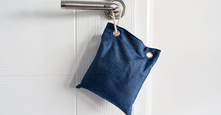 Petit sac bleu accroché à une poignée de porte par une corde