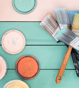 Différents pots de peinture et pinceaux sur une table en bois