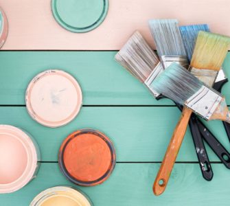 Différents pots de peinture et pinceaux sur une table en bois