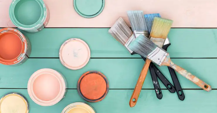 Différents pots de peinture et pinceaux sur une table en bois