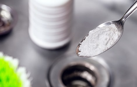 Cuillère remplie de soude pour nettoyer l'évier de la cuisine