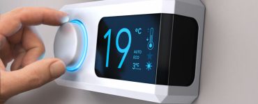 Main tournant un bouton de thermostat pour régler la température de la maison