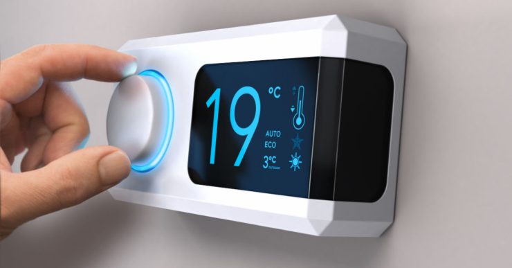 Main tournant un bouton de thermostat pour régler la température de la maison