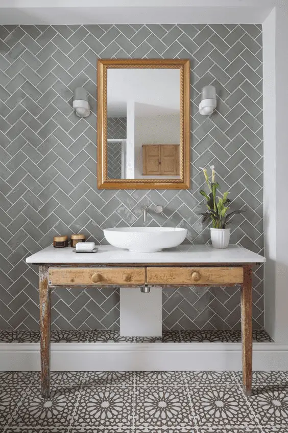 Dans une salle de bain au design actuel, c’est une ancienne table en bois qui sert de support pour la vasque