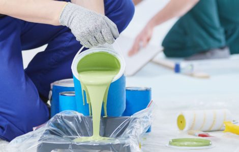 Un homme verse de la peinture verte dans un plateau de peinture en utilisant un filtre transparent