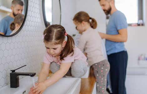 Un homme et deux petites filles se lavant les mains dans la salle de bain
