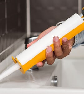 Un homme applique un joint d'étanchéité en silicone avec un pistolet