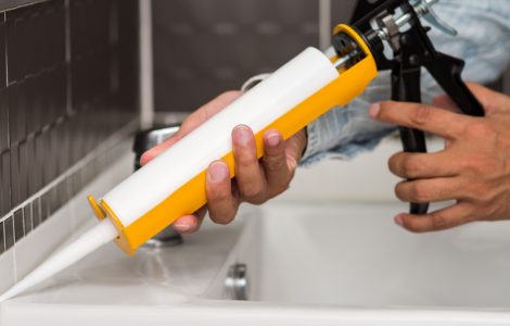 Un homme applique un joint d'étanchéité en silicone avec un pistolet