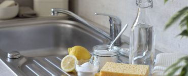 Vinaigre, citron, éponge, brosse à dents et serviettes sur l'évier de cuisine